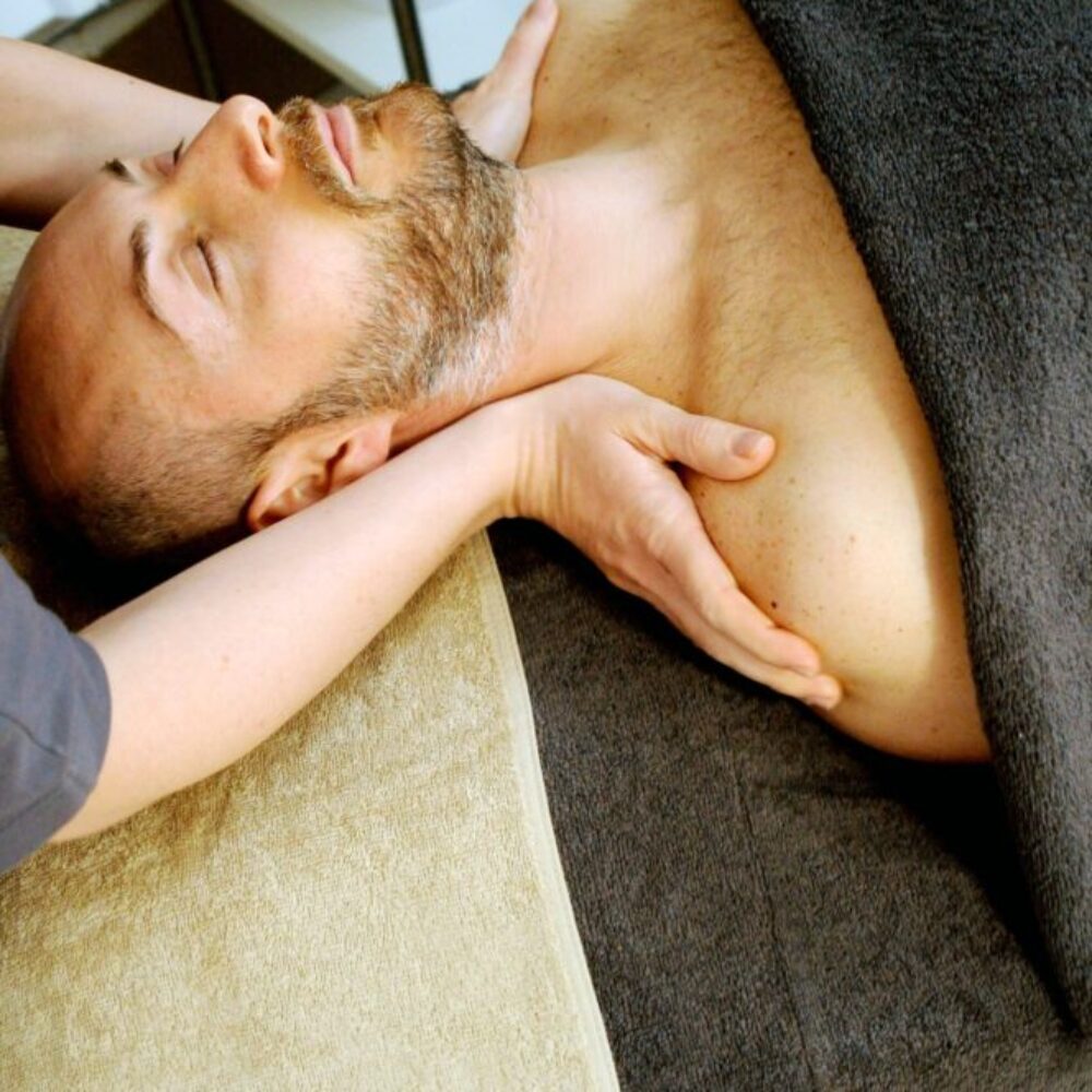 Therapeut:in dehnt den Halsbereich eines Patienten