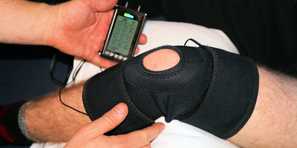 Bandagiertes Knie mit Elektrotherapiegerät